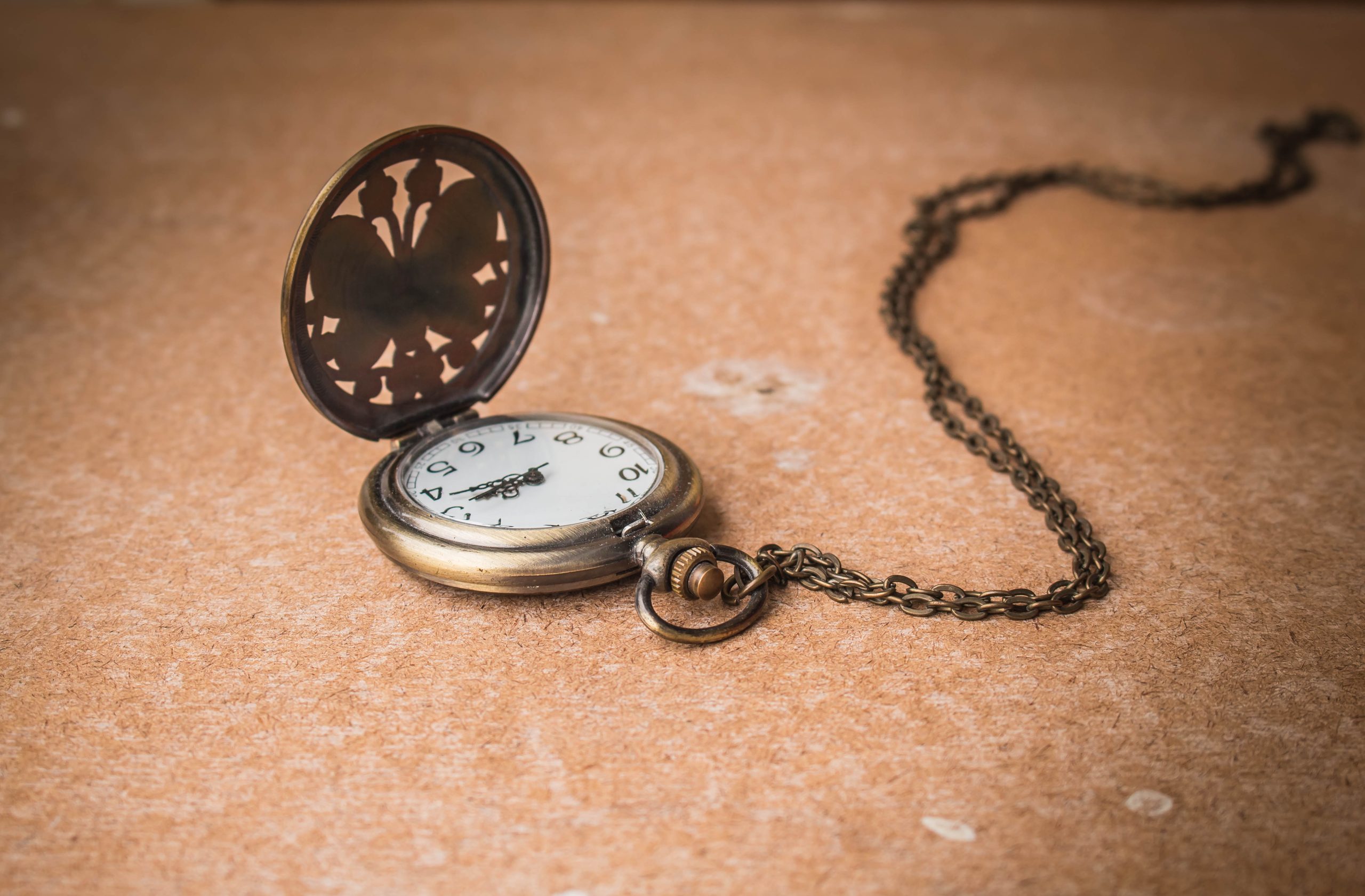 Antique Pocket Watch with Chain on Brown Surface